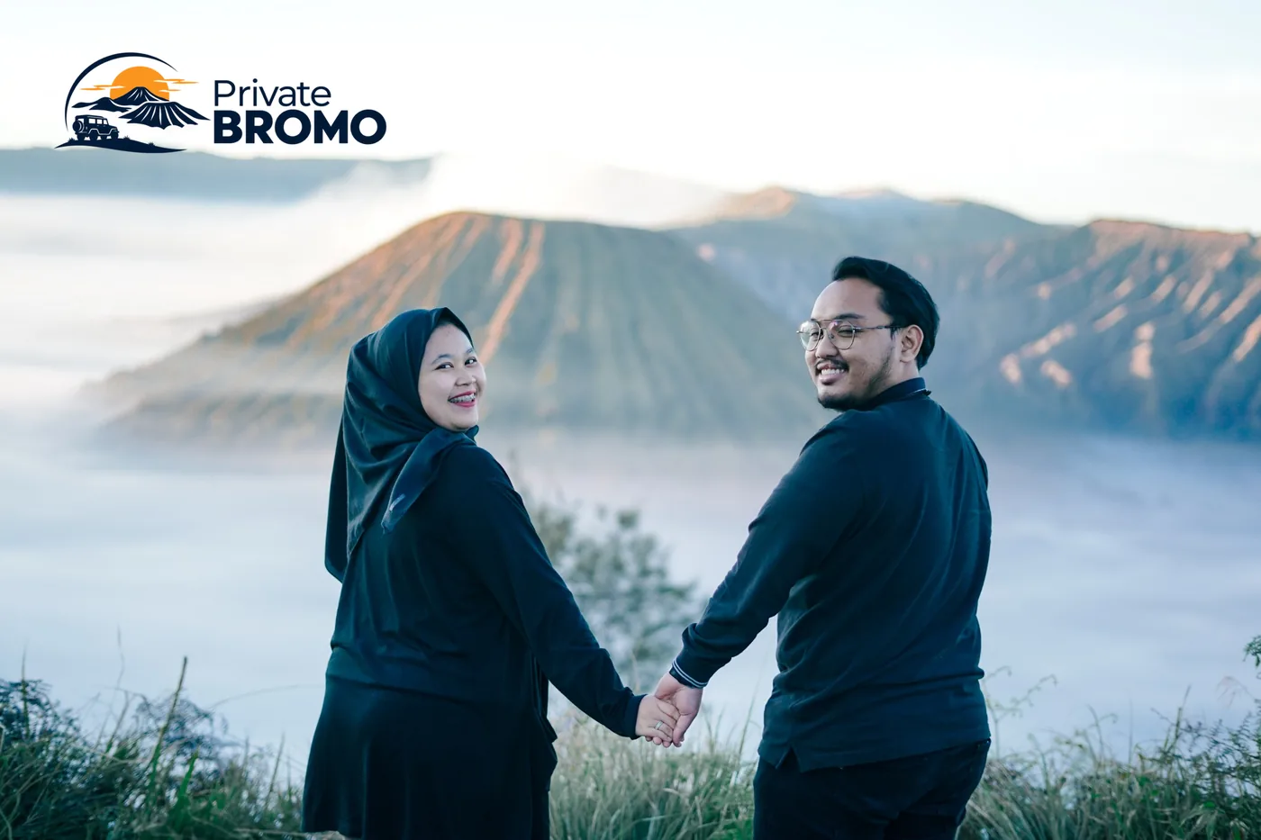 Pasangan berpegangan tangan dengan latar Gunung Bromo